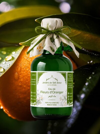 eau de fleur d’oranger Jardins de Sidi Amor en bouteille verte, présenté sur fond naturel avec orange et feuilles, eau florale 100% pure fabriquée en Tunisie